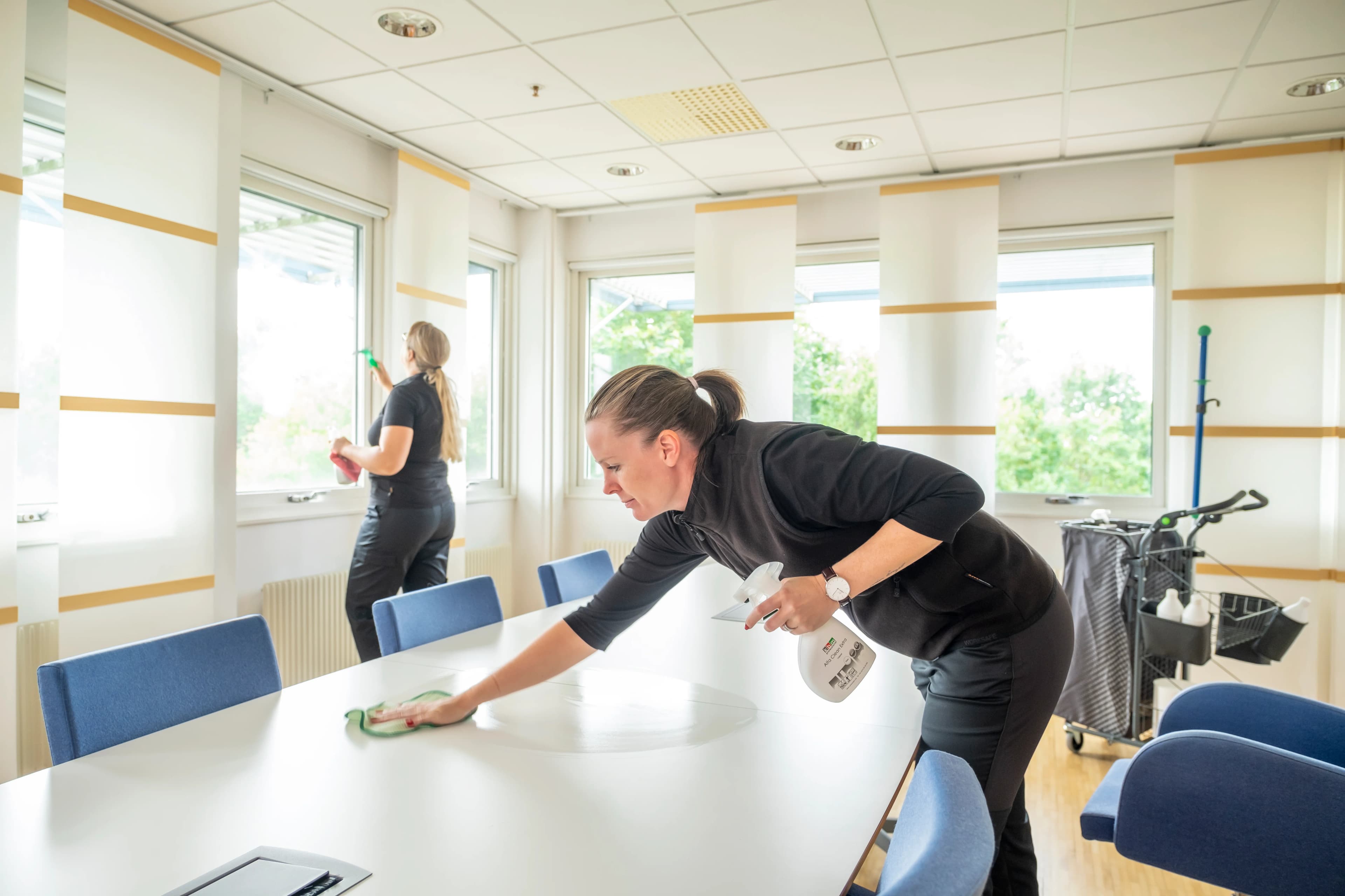 Två städare som städar ett mötesrum